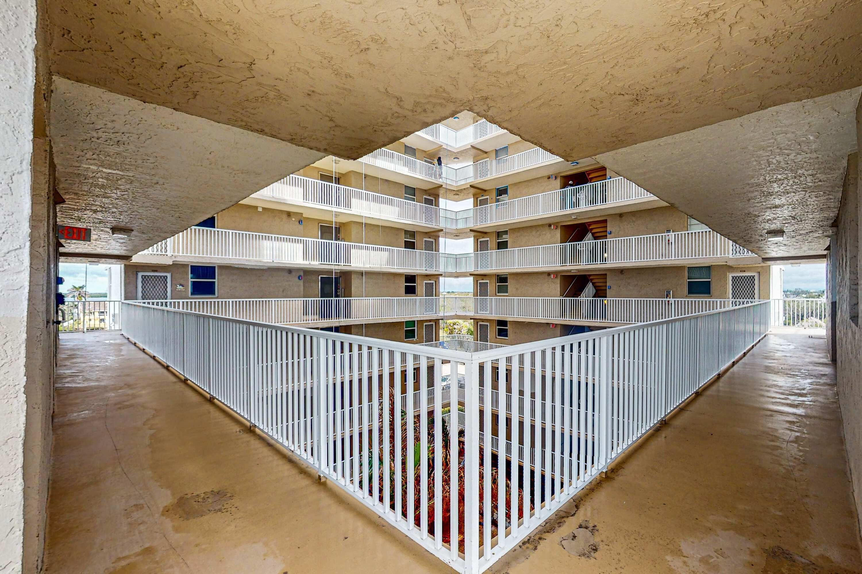 Un edificio a più livelli con un cortile centrale, ringhiere bianche e balconi.