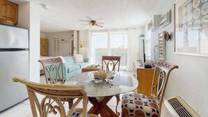 Un coin repas avec une table ronde, des chaises et un ventilateur de plafond.