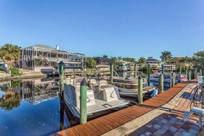 A marina with docked boats, a covered structure, and a wooden walkway. - A Fully Remodeled Gulf Retreat — Stylish Comforts Steps from the Shore. (Bonita Springs)