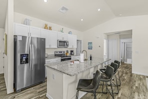 Una cocina moderna con una isla central, electrodomésticos de acero inoxidable y asientos tipo barra.