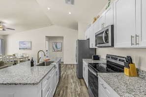 A modern kitchen with granite countertops, stainless steel appliances, and white cabinetry. - Cape Coral Retreat | Heated Pool, 2 King Suites & Dog-Friendly Game Room (Cape Coral)