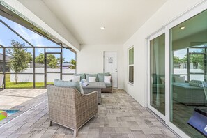 Un patio cubierto con mobiliario de mimbre, una piscina y vistas del barrio.