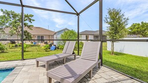 Un patio couvert avec deux chaises longues et une piscine.