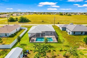 Zona residencial con casas, piscina y un amplio campo cubierto de césped.