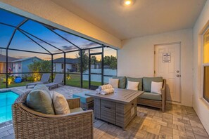 A covered outdoor patio with wicker furniture, a pool, and a view of neighboring houses. - Cape Coral Retreat | Heated Pool, 2 King Suites & Dog-Friendly Game Room (Cape Coral)