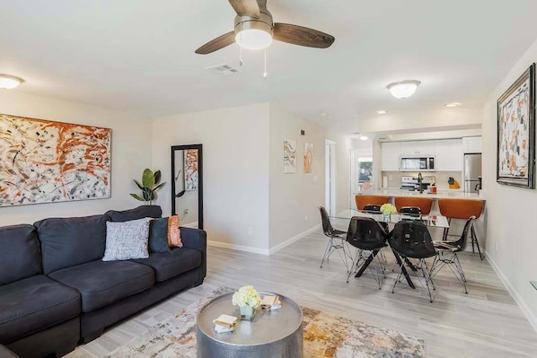 Un salon moderne comprenant un canapé, une table basse et un coin repas avec des chaises.