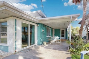 A house with a covered porch, a sliding glass door, and a small outdoor seating area. - Old Florida bungalow with WiFi, AC, washer/dryer, & patio - walk to beach (Englewood)