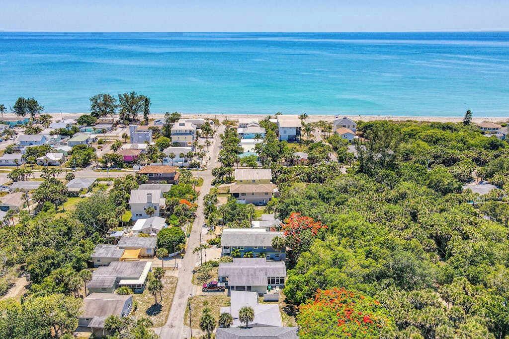 A coastal residential area with houses, a beach, and a clear view of the ocean.