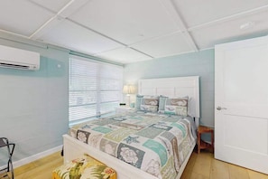 A bedroom with a bed, a nightstand, a lamp, a chair, and an air conditioning unit. - Old Florida bungalow with WiFi, AC, washer/dryer, & patio - walk to beach (Englewood)