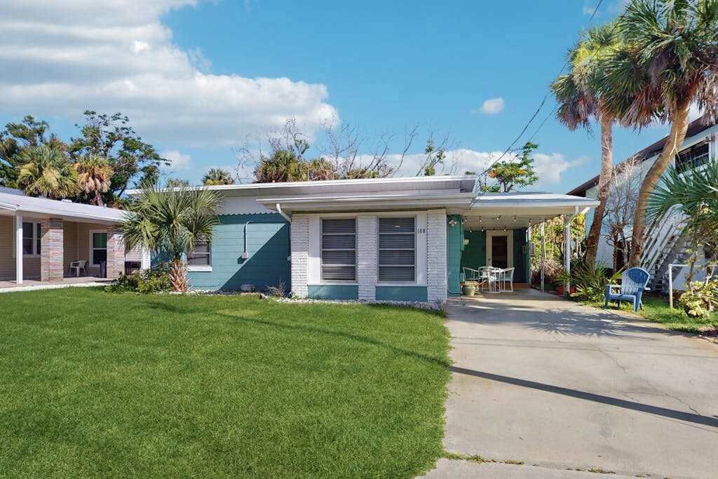 A single-story house with a front porch, a small lawn, and a clear sky.