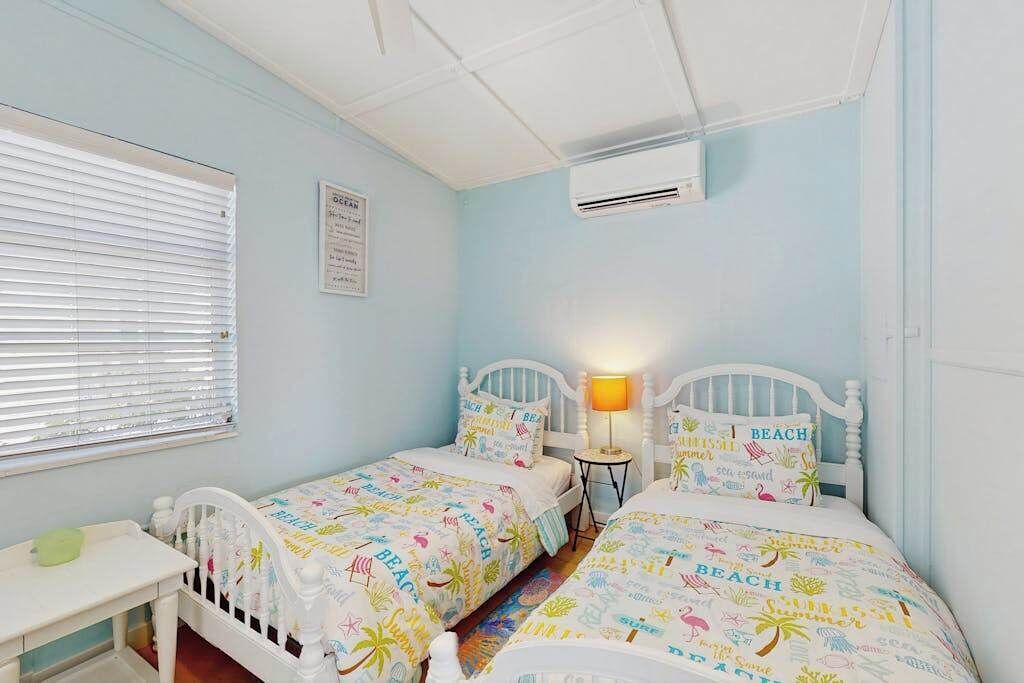 A bedroom with two beds, a small table, and a lamp.