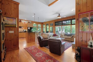 A spacious living area with a fireplace, a sofa, and a coffee table. There is a kitchen with wooden cabinets and a dining area. - Lake Escape - Dawsonville,GA (Jasper)