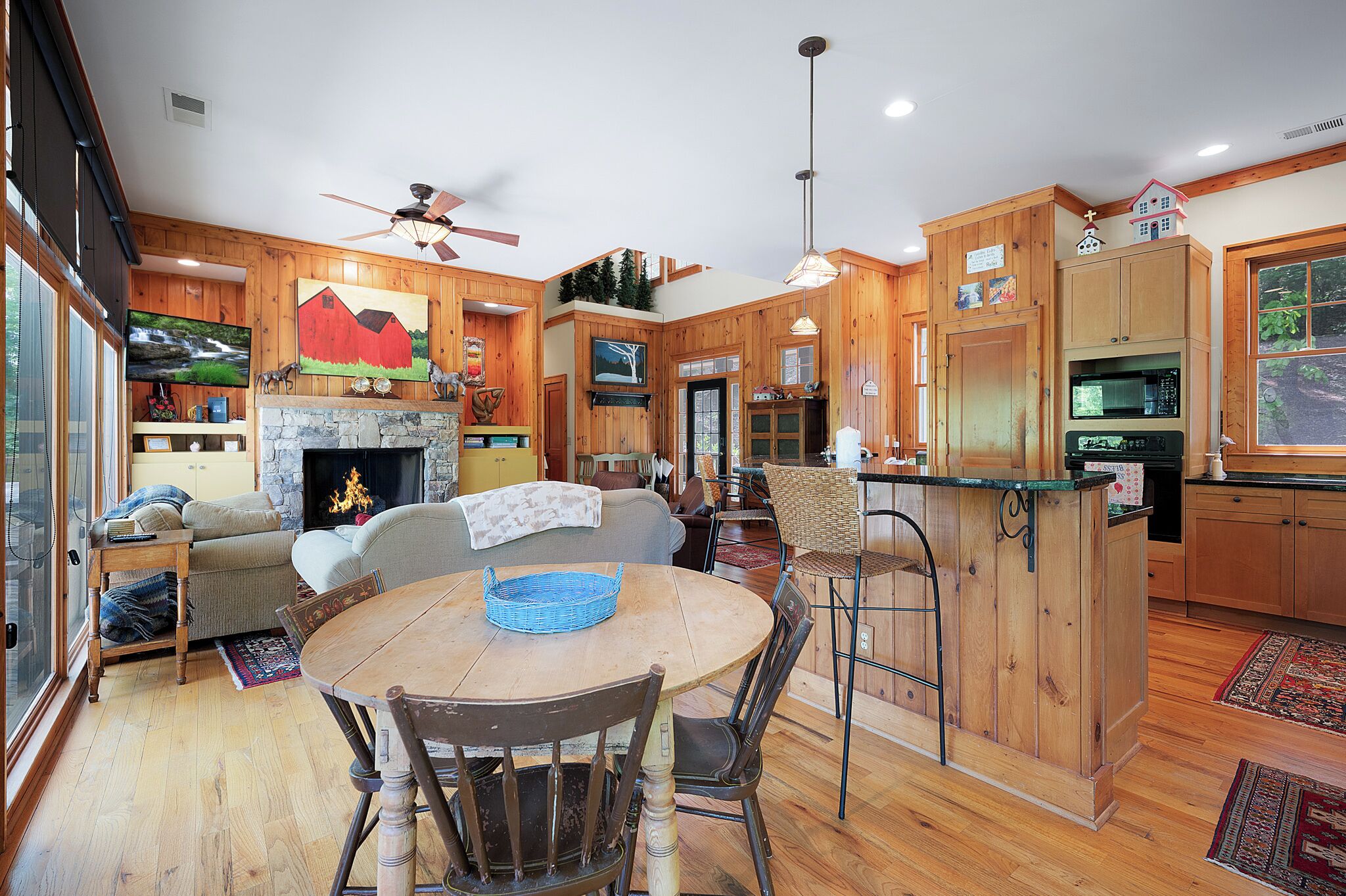 A wooden interior with a dining table, chairs, a fireplace, and a kitchen area.