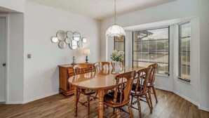 Un comedor con una mesa y sillas de madera, una araña y un conjunto de espejos colgados en la pared.