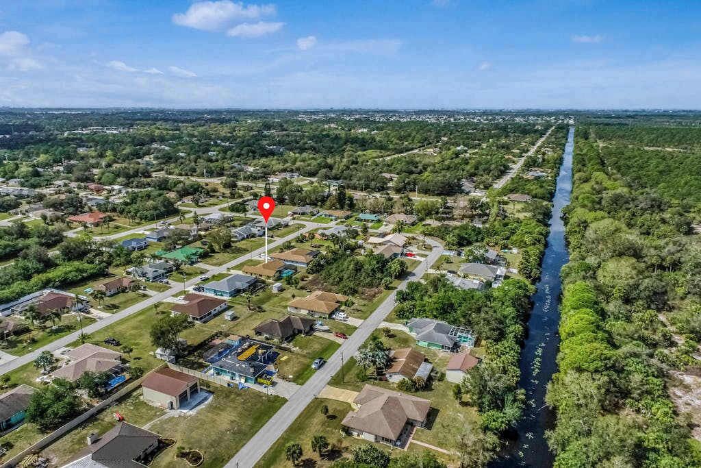 An aerial view of a residential area with houses, a river, and a red location marker.