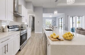 Cocina moderna con armarios blancos, electrodomésticos de acero inoxidable y una isla grande con limones.