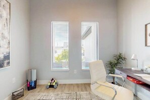A room with a desk, chair, two windows, a plant, and a rug. - Brand new, Inviting home with private pool and complimentary pool heat (Cape Coral)