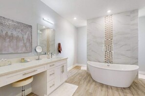 A modern bathroom with a freestanding bathtub, a large mirror, and a vanity with drawers. - Brand new, Inviting home with private pool and complimentary pool heat (Cape Coral)