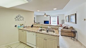 Eine Küche mit Kochinsel, Deckenventilator und Essbereich mit Couch und Tisch.