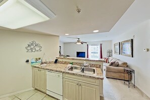 A kitchen with a central island, a ceiling fan, and a dining area with a couch and table. - Dog-friendly lake-view getaway with pool & all-suite layout - walkable locale (Cape Coral)