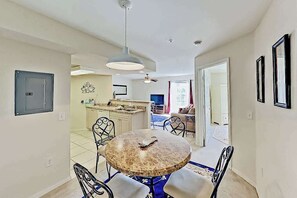 A dining area with a round table and chairs, a kitchen in the background, and a ceiling fan. - Dog-friendly lake-view getaway with pool & all-suite layout - walkable locale (Cape Coral)