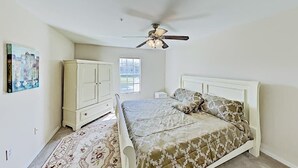 Ein Schlafzimmer mit Bett, Deckenventilator, Fenster und Schrank.