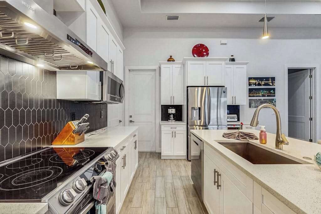 A modern kitchen with a central island, stainless steel appliances, and a tiled backsplash.
