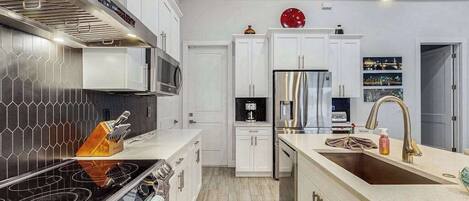 A modern kitchen with a central island, stainless steel appliances, and a tiled backsplash.