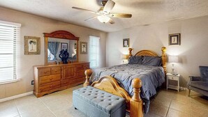 Ein Schlafzimmer mit Bett, Schminktisch, Spiegel, Deckenventilator und Nachttisch.