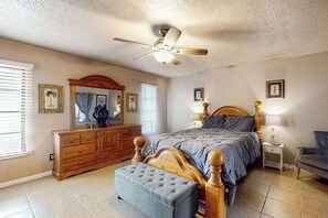 A bedroom with a bed, a dresser, a mirror, a ceiling fan, and a nightstand. - Coastal home near downtown w/ private pool, patio, grill, W/D, cable-Dogs ok (Cape Coral)