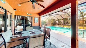 Ein überdachter Außenbereich mit Pool, Sitzgelegenheiten und Deckenventilator.