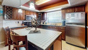 Eine Küche mit Holzausstattung, einem Edelstahlkühlschrank und einem Essbereich mit Tisch und Stühlen.