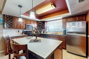 Una cocina con armarios de madera, un refrigerador de acero inoxidable y un comedor con mesa y sillas.
