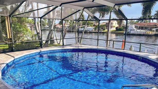 En swimmingpool med utsikt över en sjö eller ett hav och palmer.