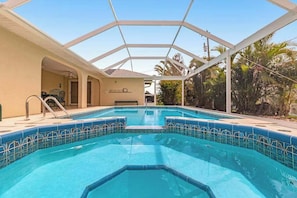 A swimming pool with a glass ceiling, surrounded by palm trees and a building with a beige exterior. - Spacious home with a private pool, pool spa, washer/dryer, & AC (Cape Coral)