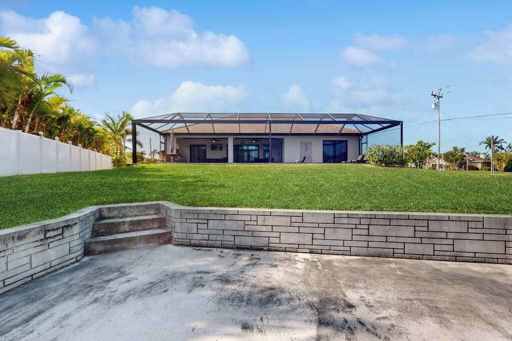 A modern house with a flat roof, a covered patio, and a well-maintained lawn.