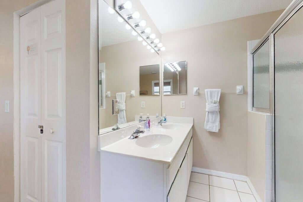 A bathroom with two sinks, a large mirror, and a shower area.