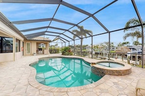 Piscina coberta ao ar livre com hidromassagem, rodeada por um terraço e vista para uma marina.