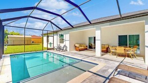 Una piscina techada con techo de vidrio, mobiliario exterior y vistas del entorno.