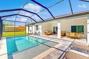 Ein überdachter Swimmingpool mit Glasdach, Gartenmöbeln und Blick auf die Umgebung.