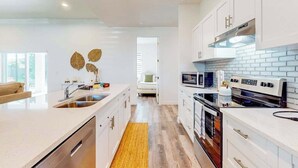Una cocina moderna con armarios blancos, una isla central con un fregadero, microondas y estufa.