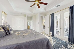 A bedroom with a bed, a ceiling fan, a door, and a view to a balcony. - Beautiful home with private pool, waterfront views & home theater (Cape Coral)