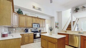 A kitchen with wooden cabinets, a stainless steel oven, a microwave, and a dishwasher. - Beautiful home with private pool, waterfront views & home theater (Cape Coral)