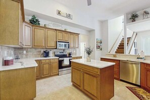 A kitchen with wooden cabinets, a stainless steel oven, a microwave, and a dishwasher. - Beautiful home with private pool, waterfront views & home theater (Cape Coral)