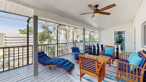 Eine überdachte Terrasse mit Holzmöbeln, einem Deckenventilator und Blick ins Freie.