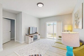 Een moderne woonkamer met een flatscreen televisie, een bijzettafeltje en een bank.