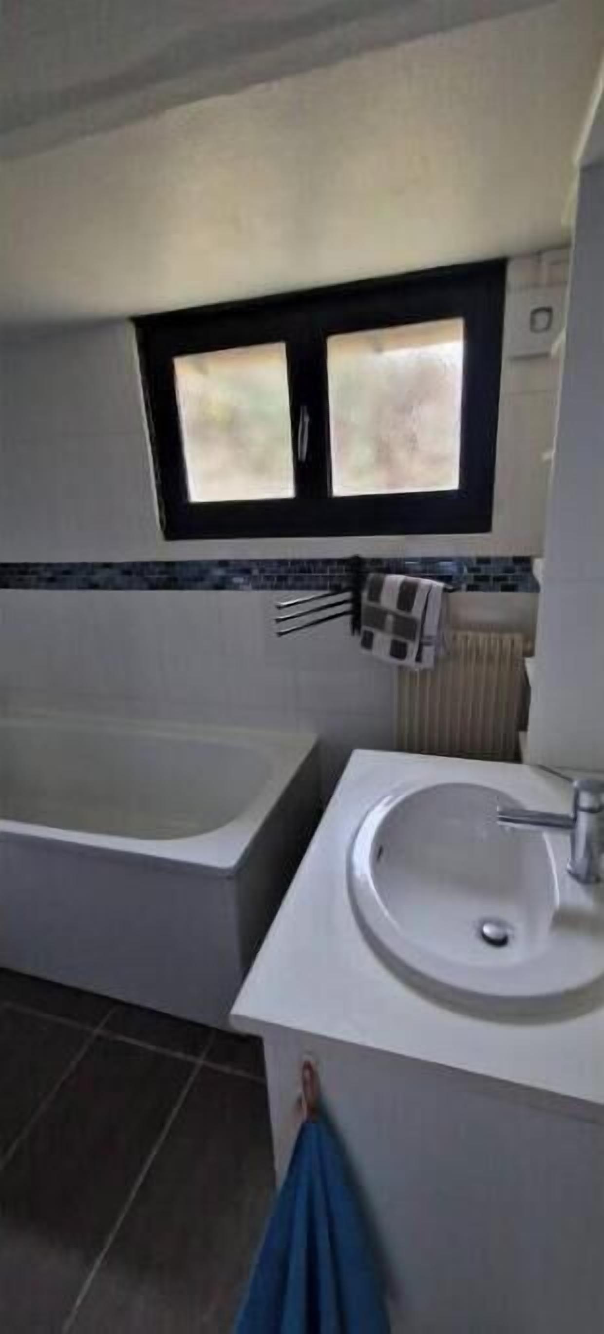 Une salle de bain avec une baignoire, un lavabo et une fenêtre au-dessus du lavabo.