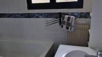 Une salle de bain avec une baignoire, un lavabo et une fenêtre au-dessus du lavabo.