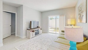 A modern living room with a flat-screen TV, a sofa, a coffee table, and a lamp. - Dog friendly duplex with hot tub, internet, and washer and dryer (Englewood)