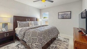 A bedroom with a bed, a nightstand, a dresser, a ceiling fan, and a window with blinds. - Dog friendly duplex with hot tub, internet, and washer and dryer (Englewood)